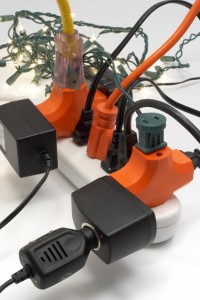Overloaded electrical power strip with Christmas lights in background