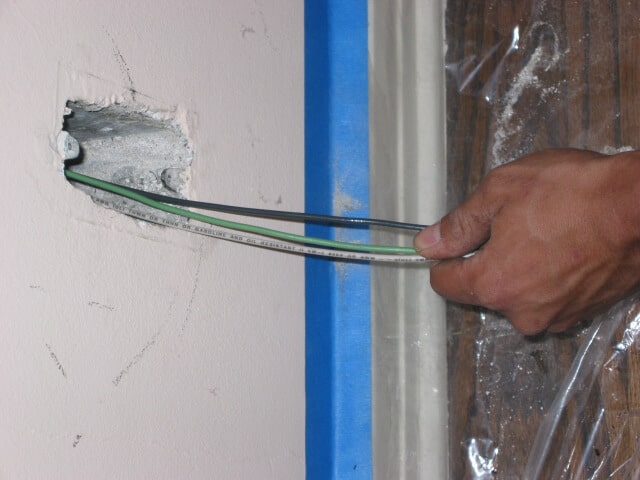 electrician pulling wires through wall
