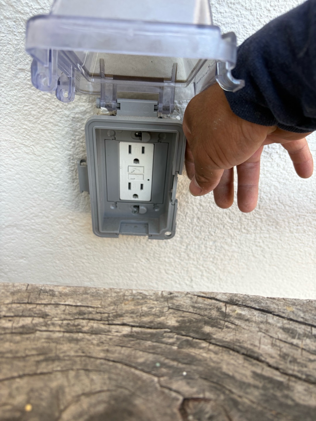 An outdoor GFCI receptacle installed inside a clear weatherproof while-in-use cover.